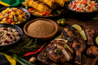 Jamaican jerk într-un bol, lângă preparate la grătar cu carne și legume