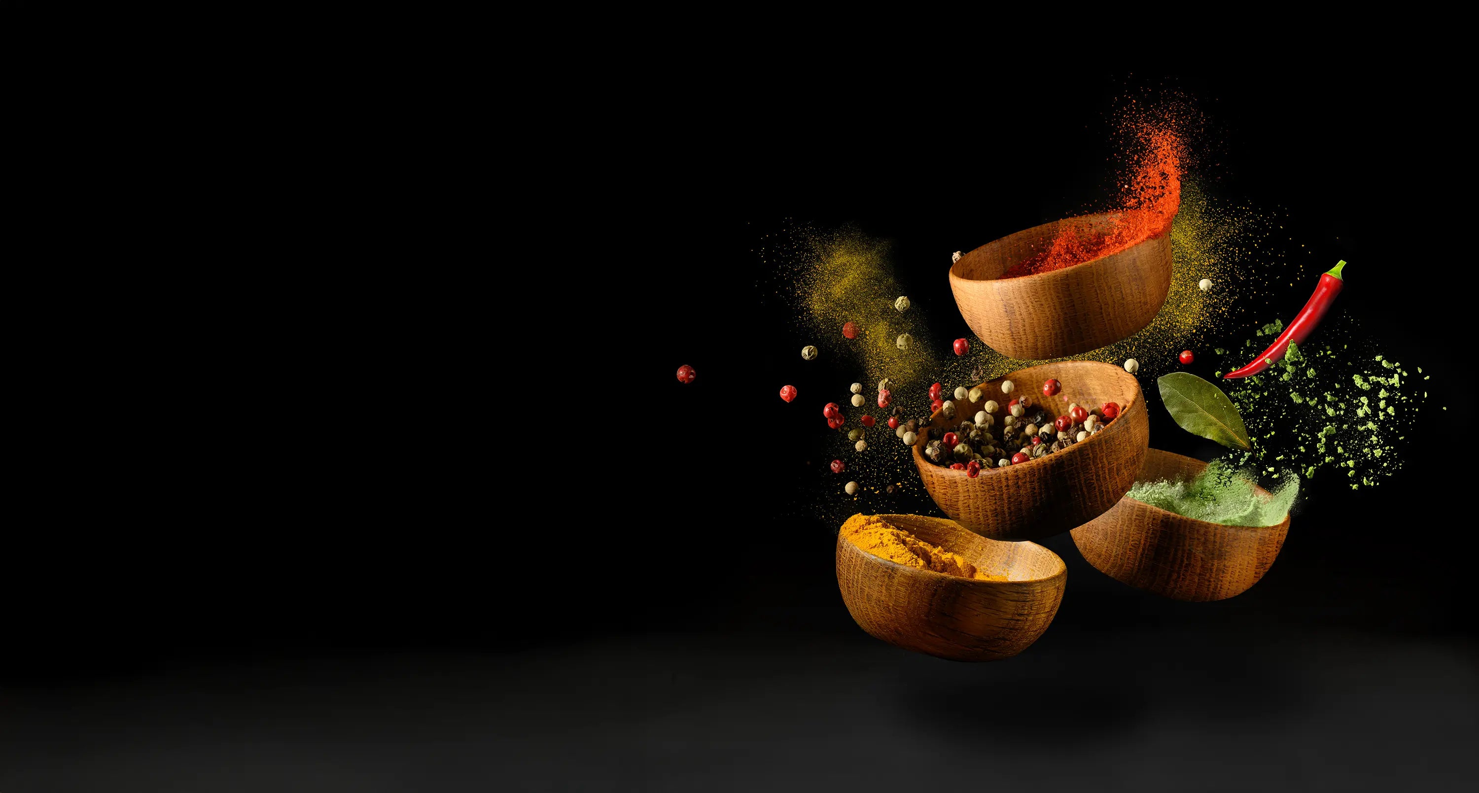 Wooden bowls with colorful spices on a black background